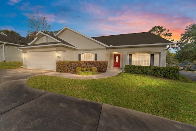 ranch-style home featuring a garage and a lawn