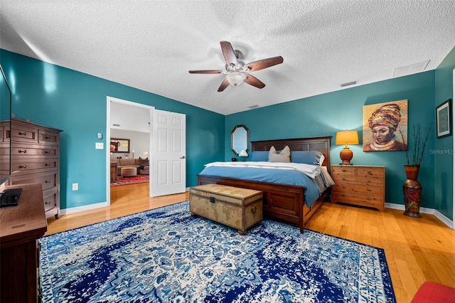 bedroom with visible vents, baseboards, ceiling fan, wood finished floors, and a textured ceiling