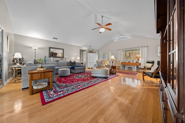 living area with visible vents, vaulted ceiling, light wood finished floors, and ceiling fan