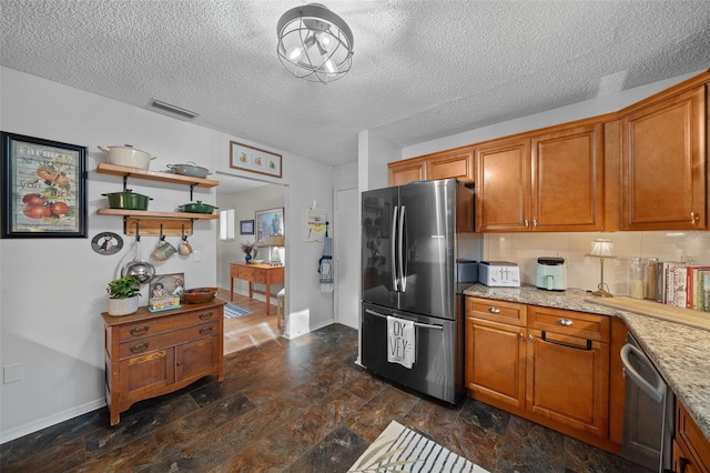 kitchen with visible vents, appliances with stainless steel finishes, brown cabinets, and stone finish flooring