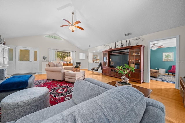 living room featuring vaulted ceiling, ceiling fan, wood finished floors, and visible vents