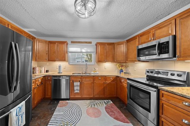 kitchen with tasteful backsplash, brown cabinetry, light stone countertops, stainless steel appliances, and a sink