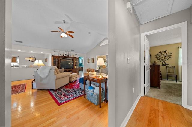 living room with lofted ceiling, ceiling fan, wood finished floors, visible vents, and baseboards