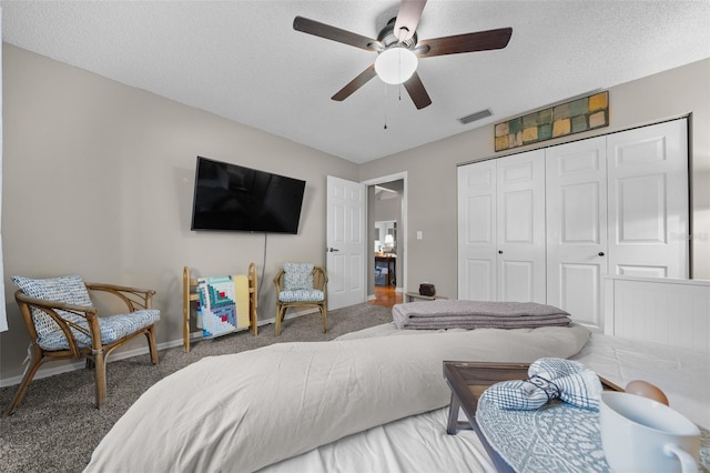 carpeted bedroom with a textured ceiling, ceiling fan, a closet, and visible vents