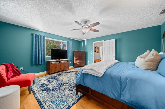 bedroom with a textured ceiling, wood finished floors, a ceiling fan, and baseboards