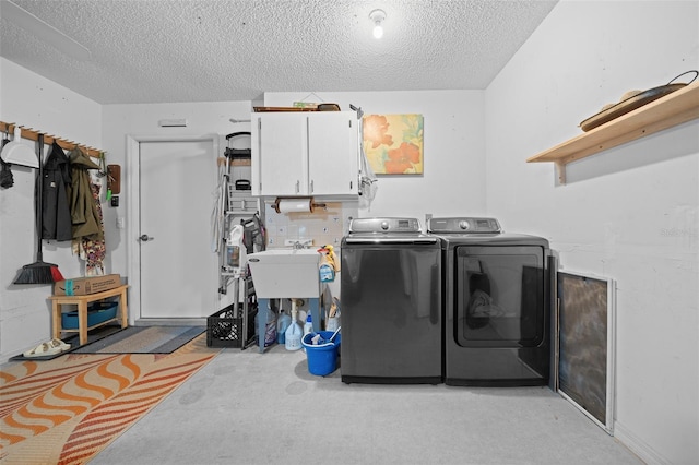 laundry room featuring a textured ceiling, separate washer and dryer, and cabinet space