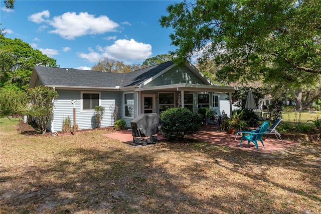 rear view of house featuring a yard and a patio