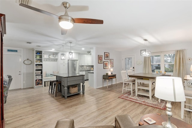 dining area with light wood-type flooring and ceiling fan