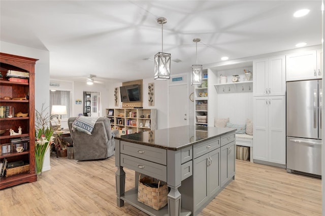 kitchen with white cabinetry, hanging light fixtures, stainless steel refrigerator, gray cabinets, and dark stone counters