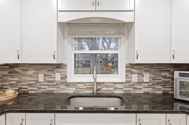 kitchen featuring white cabinetry, sink, and dark stone countertops