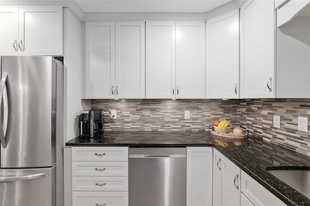 kitchen featuring backsplash, white cabinetry, stainless steel appliances, and dark stone countertops