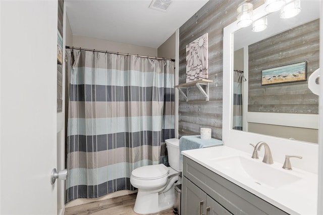 bathroom with wooden walls, vanity, toilet, and wood-type flooring