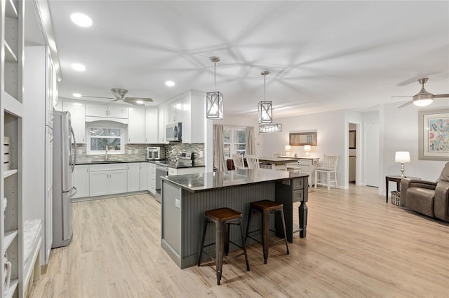8723 SW 93rd Ln Unit C, Ocala, FL 34481 - kitchen featuring a kitchen bar, a ceiling fan, stainless steel appliances, and light wood-style floors