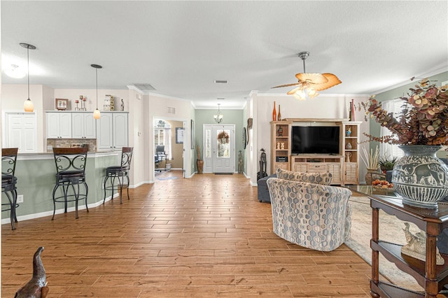 living room with ceiling fan, ornamental molding, and light hardwood / wood-style floors