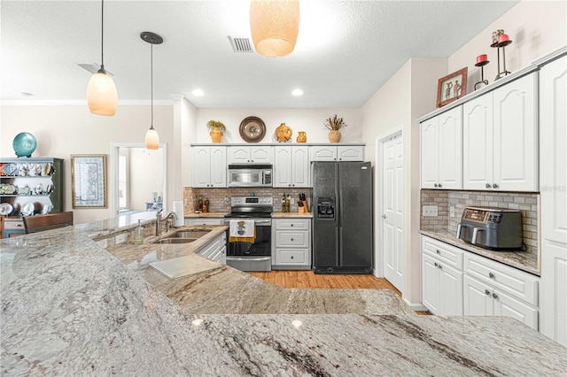 kitchen with white cabinetry, backsplash, stainless steel appliances, light stone counters, and decorative light fixtures