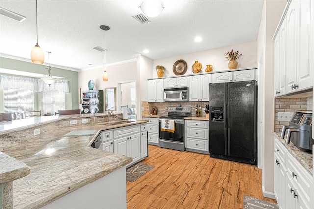 kitchen featuring pendant lighting, sink, white cabinetry, backsplash, and stainless steel appliances