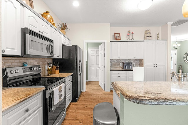 kitchen with white cabinetry, light hardwood / wood-style flooring, appliances with stainless steel finishes, light stone countertops, and backsplash