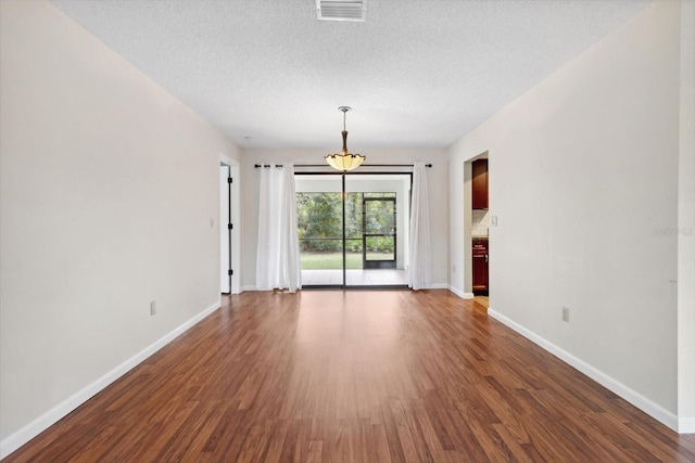 unfurnished living room featuring dark wood-type flooring and a textured ceiling