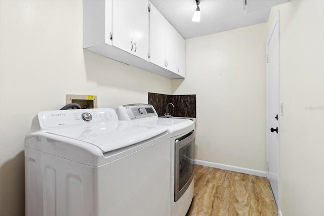 laundry room with cabinets, light wood-type flooring, and separate washer and dryer