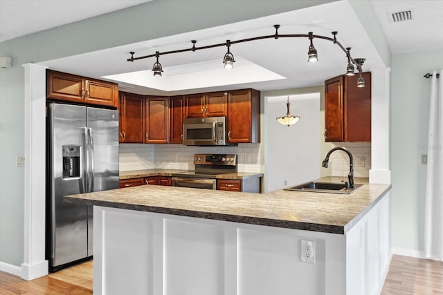 kitchen with stainless steel appliances, sink, backsplash, kitchen peninsula, and light wood-type flooring