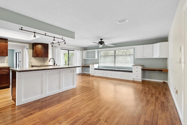 kitchen featuring light hardwood / wood-style flooring, sink, backsplash, a textured ceiling, and built in desk