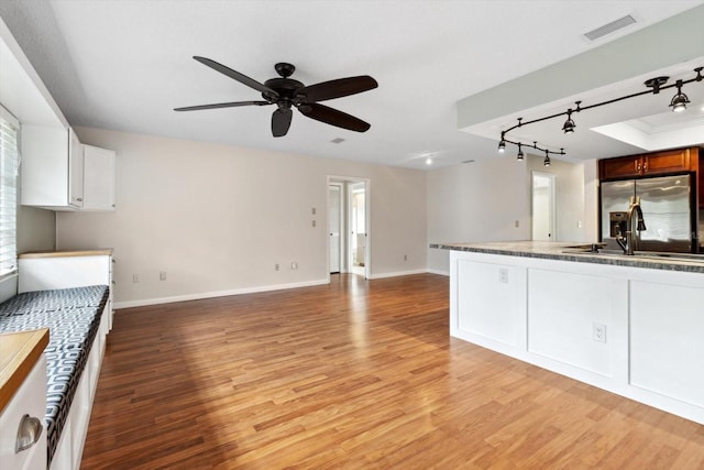 kitchen with white cabinets, light hardwood / wood-style floors, sink, stainless steel fridge, and ceiling fan