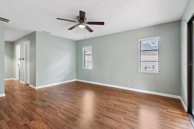 empty room with wood-type flooring, plenty of natural light, and a textured ceiling