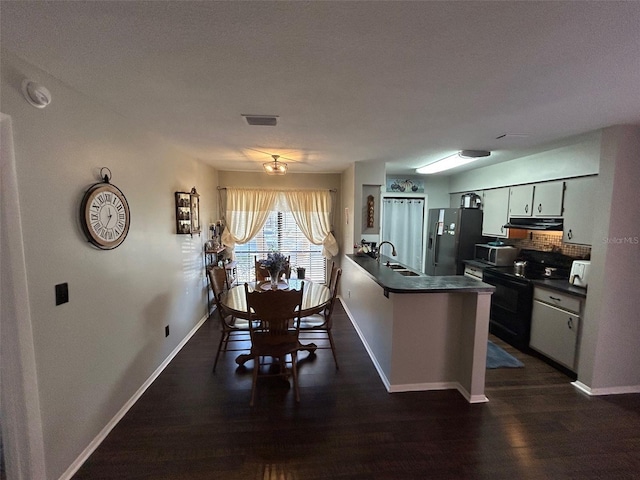 kitchen with appliances with stainless steel finishes, dark hardwood / wood-style floors, kitchen peninsula, and sink