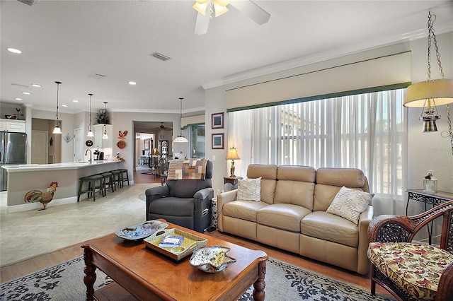 living room with ornamental molding, sink, ceiling fan, and light hardwood / wood-style floors