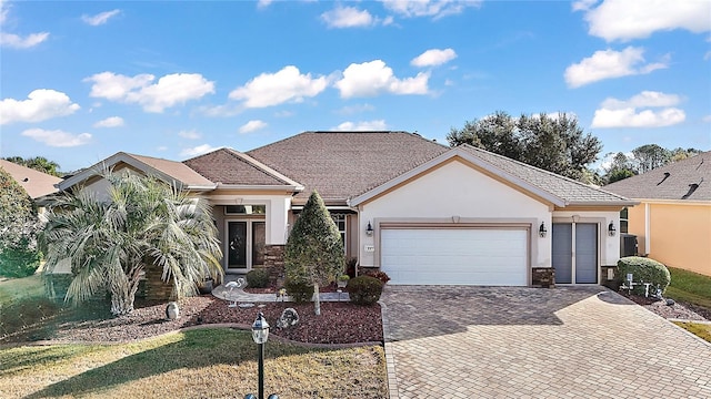 view of front of home with a garage, central AC unit, decorative driveway, and stucco siding