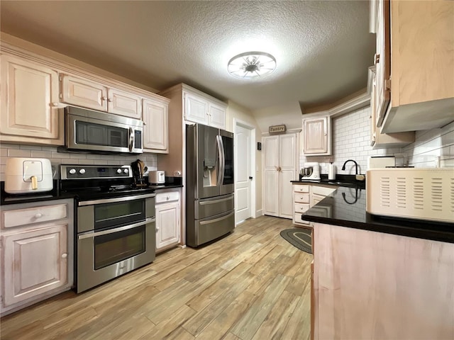 kitchen featuring stainless steel appliances, light hardwood / wood-style floors, sink, a textured ceiling, and decorative backsplash