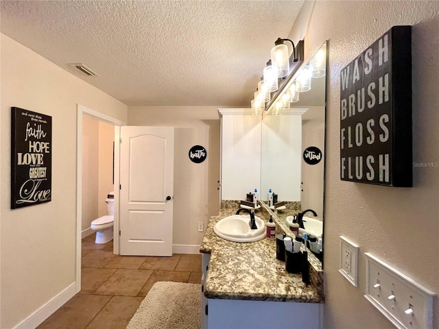 bathroom featuring toilet, a textured ceiling, and vanity