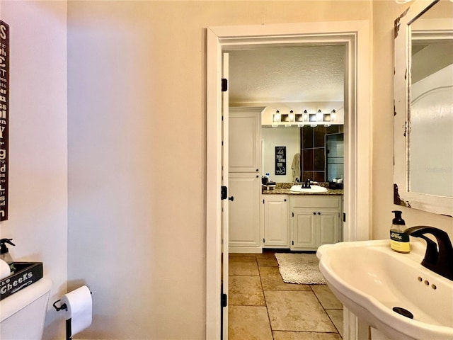 bathroom with sink, toilet, and a textured ceiling