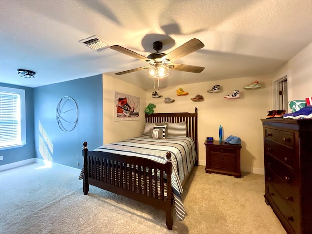 bedroom featuring a textured ceiling, light colored carpet, and ceiling fan