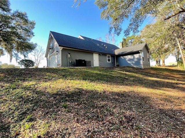 back of property featuring a lawn and central AC