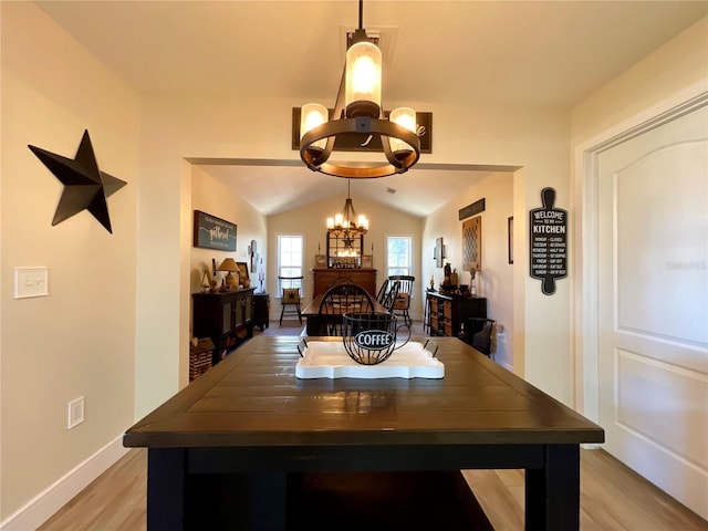 dining room with light wood-type flooring, lofted ceiling, and an inviting chandelier