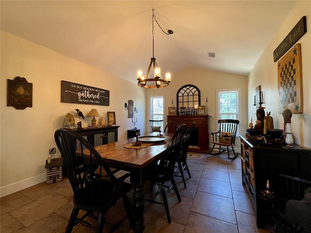 dining room featuring vaulted ceiling, dark tile patterned flooring, and a chandelier