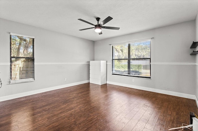 empty room featuring dark wood-type flooring, a textured ceiling, and ceiling fan