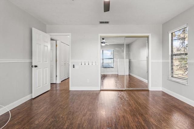 unfurnished bedroom with multiple windows, dark hardwood / wood-style flooring, a closet, and ceiling fan