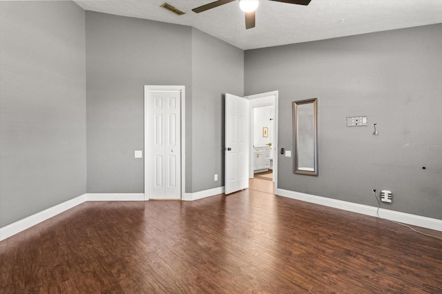 empty room with ceiling fan, dark hardwood / wood-style floors, and a high ceiling