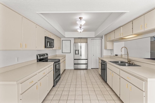 kitchen with light tile patterned flooring, stainless steel appliances, a tray ceiling, and sink