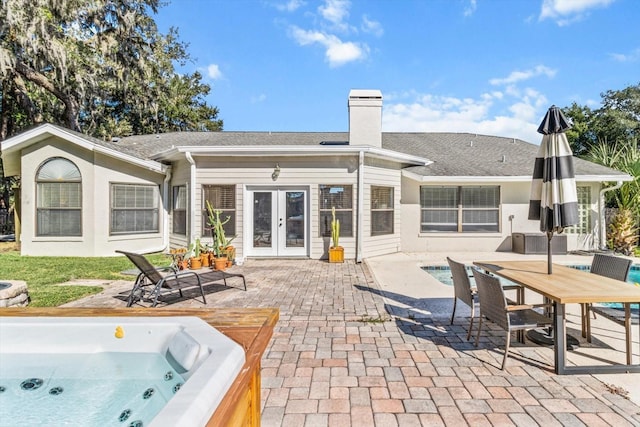 rear view of property with a hot tub, french doors, and a patio area