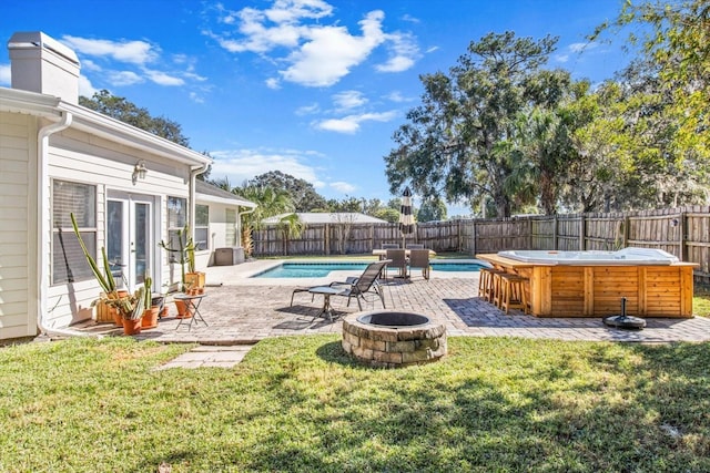 exterior space with a hot tub, a yard, and an outdoor fire pit