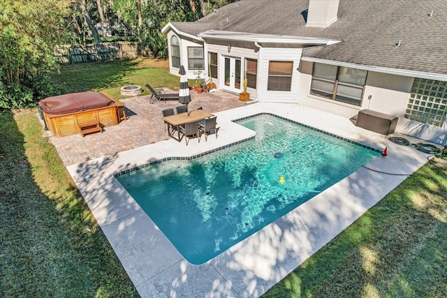 view of swimming pool with french doors, a patio, a hot tub, and a fire pit