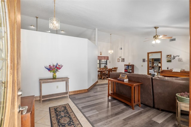 living room with lofted ceiling and ceiling fan with notable chandelier