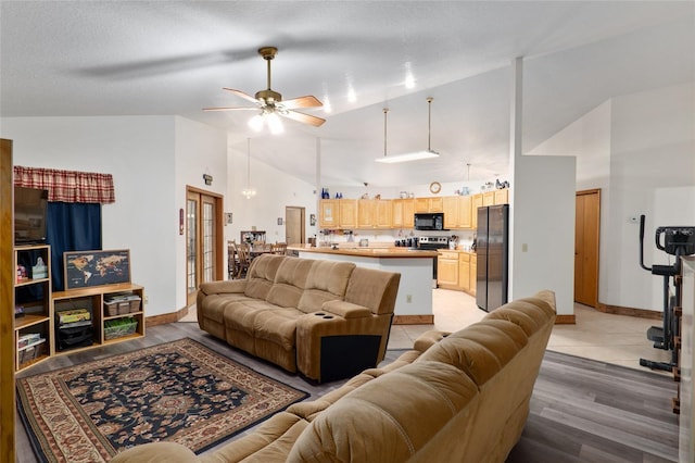 living room featuring ceiling fan, lofted ceiling, light hardwood / wood-style flooring, and a textured ceiling