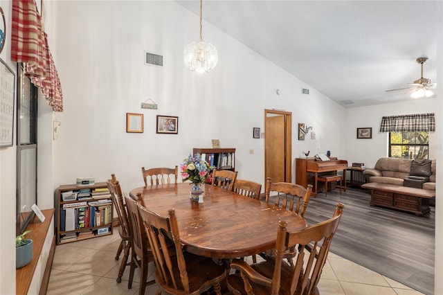 tiled dining space with ceiling fan with notable chandelier