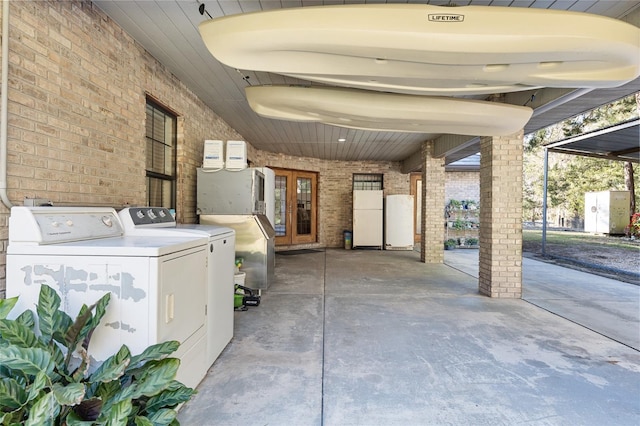 clothes washing area featuring brick wall and independent washer and dryer