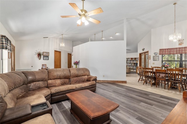 living room with ceiling fan with notable chandelier, high vaulted ceiling, and hardwood / wood-style floors