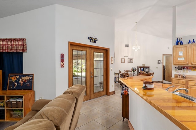 kitchen featuring pendant lighting, sink, light tile patterned floors, butcher block countertops, and french doors